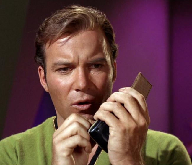 Captain Kirk using his communicator.